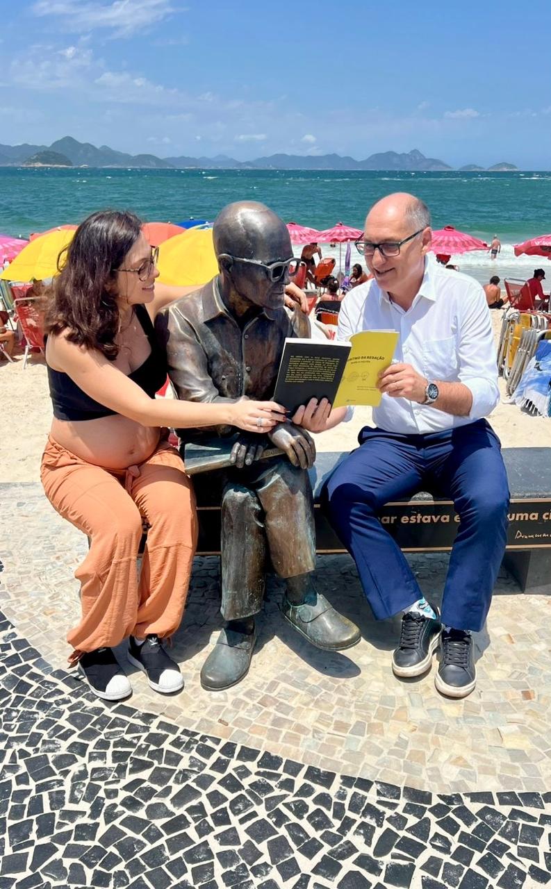 Prof. Nado e família ao lado da estátua de Carlos Drummond de Andrade, em Copacabana, lendo o Algoritmo da Redação