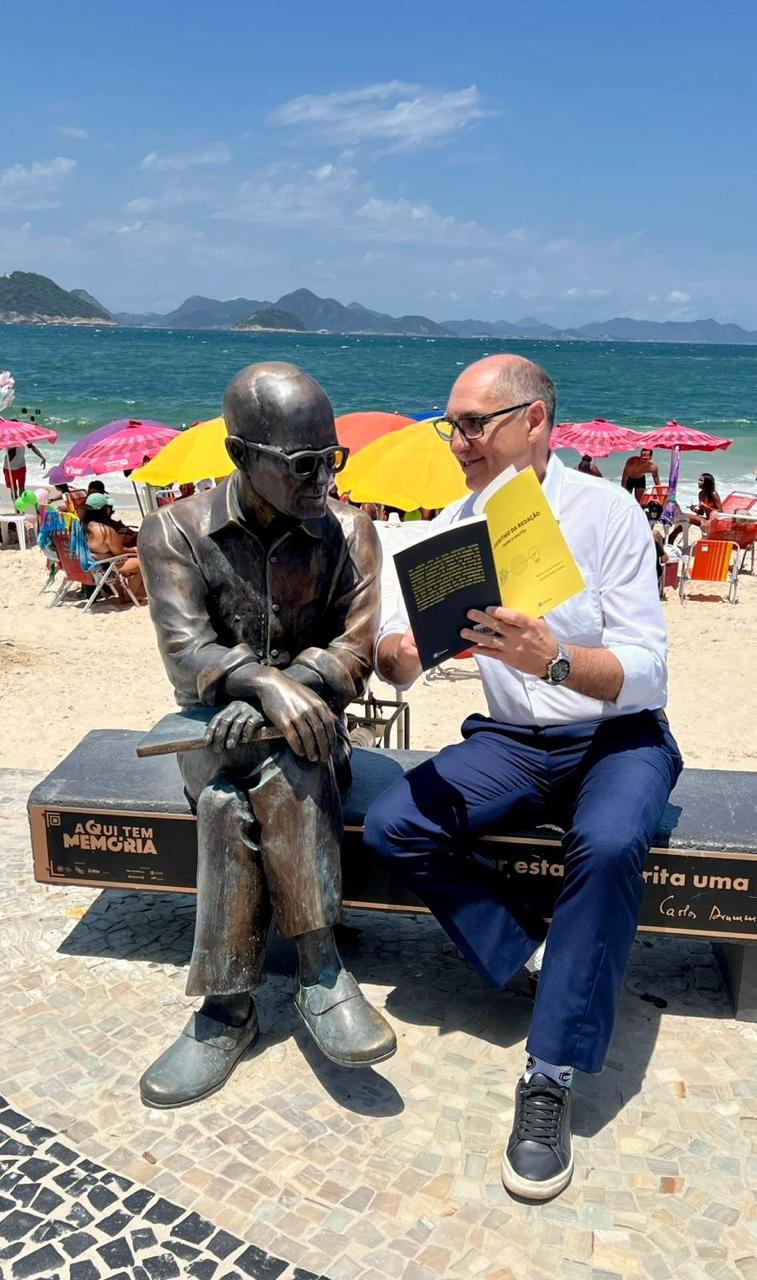 Prof. Nado lê o Algoritmo da Redação ao lado da estátua de Drummond, em Copacabana